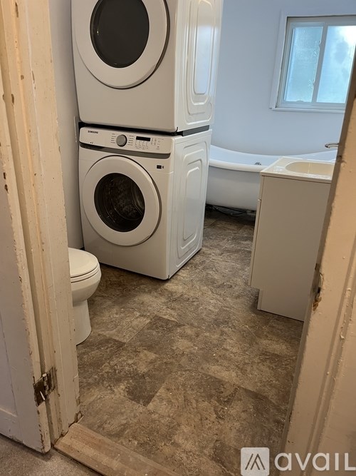 A stack of three white washing machines in a laundry room.