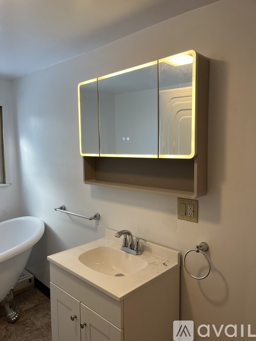 A bathroom with a sink, mirror, and bathtub.