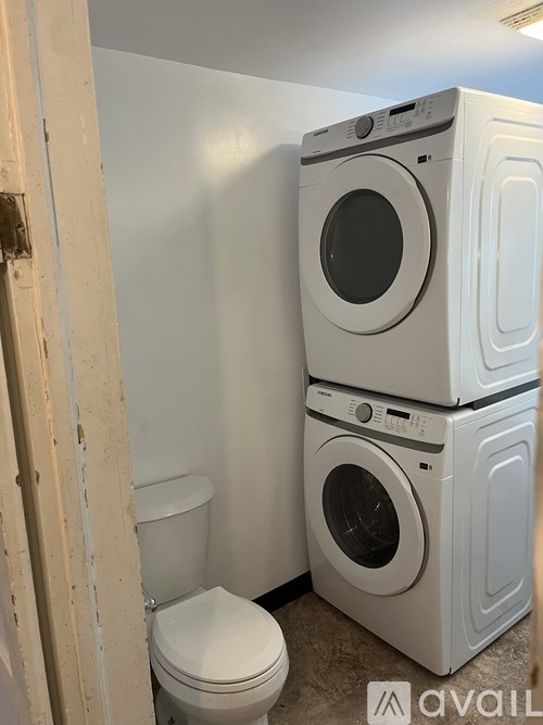 A stack of three white washing machines in a laundry room.