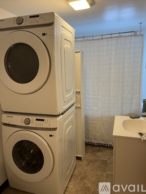 A stack of three white front loading washing machines in a laundry room.