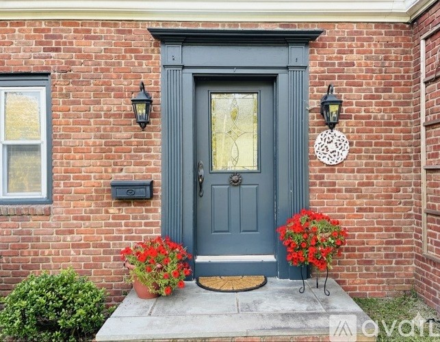 A grey door with a glass window is flanked by two black lanterns.