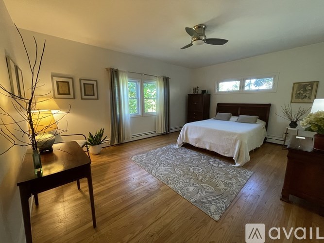 A bedroom with a bed, a table, and a ceiling fan.