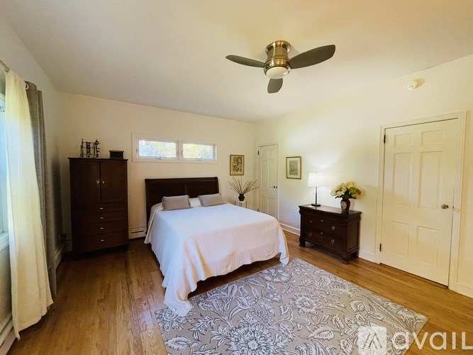 A bedroom with a bed, dresser, and ceiling fan.
