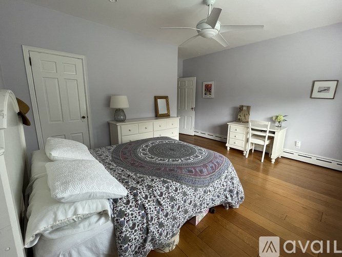 A bedroom with a bed, dresser, and ceiling fan.