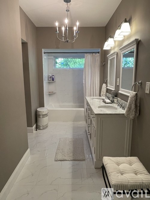 A bathroom with a chandelier, a tub, a toilet, and a sink.