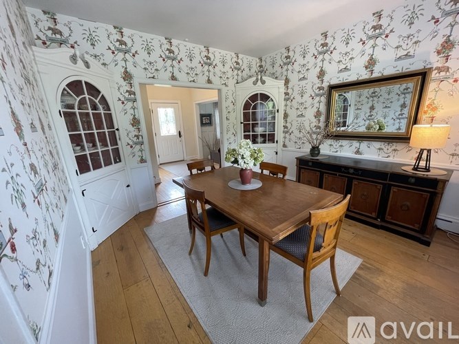 A dining room with a floral wallpaper and a wooden table.