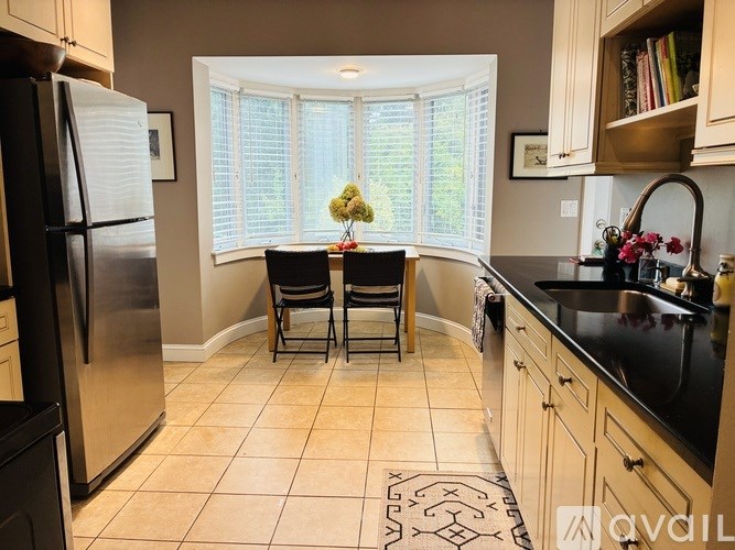 A kitchen with a black counter top and a refrigerator on the left.