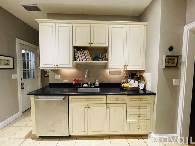 A kitchen with white cabinets and a black countertop.