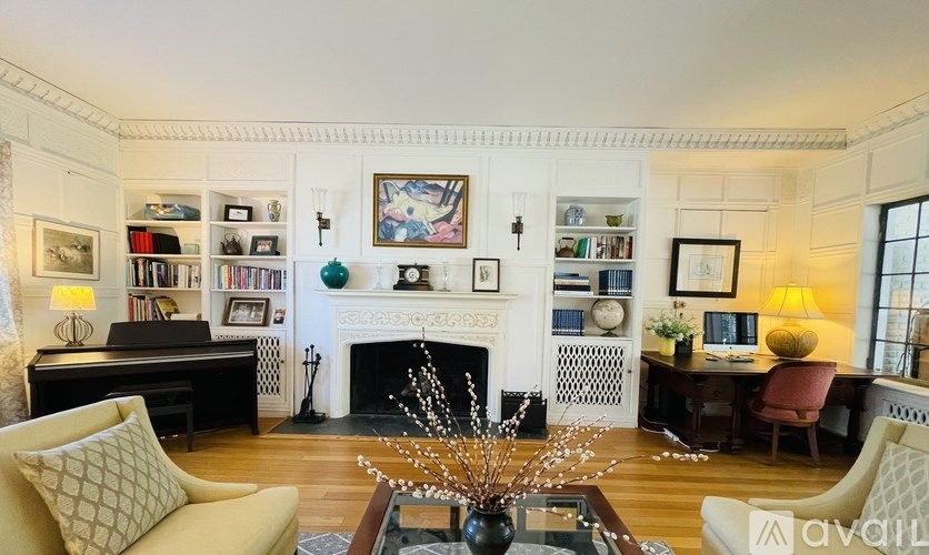 A living room with a fireplace, bookshelves, and a chair.