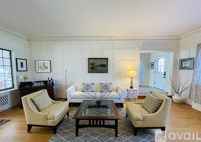 A living room with a white couch, two chairs, and a coffee table.