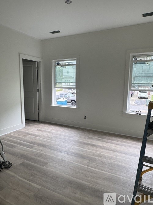 A room with a wooden floor and two windows.