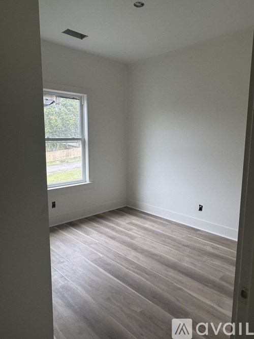 A room with a window and wooden flooring.