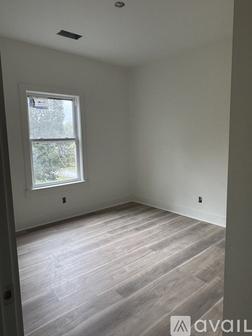 A room with a window and wooden flooring.