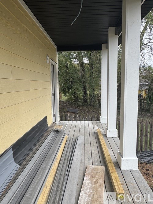 A porch with a yellow wall and grey steps.