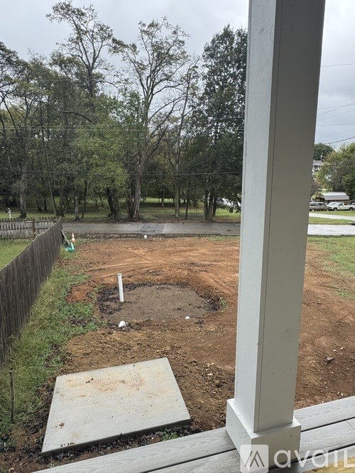 A backyard with a dirt area and a wooden fence.