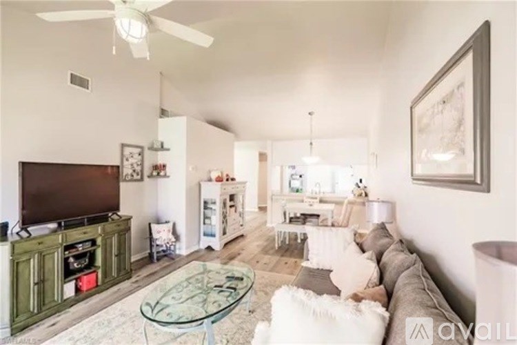 A living room with a glass coffee table and a television.