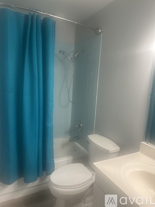A blue shower curtain hangs over a glass shower door in a bathroom.