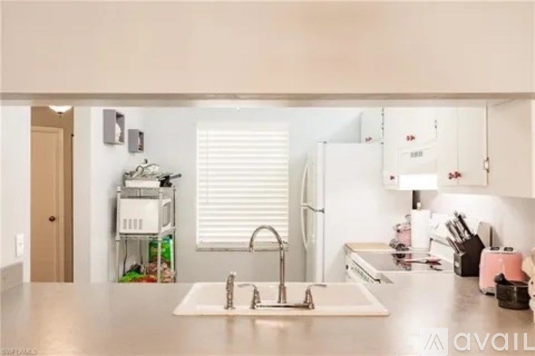 A kitchen with a sink and a window with blinds.