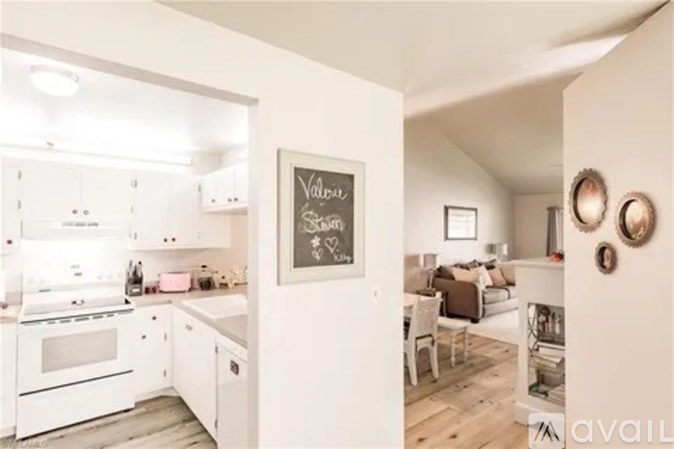 A kitchen with white appliances and a chalkboard on the wall.