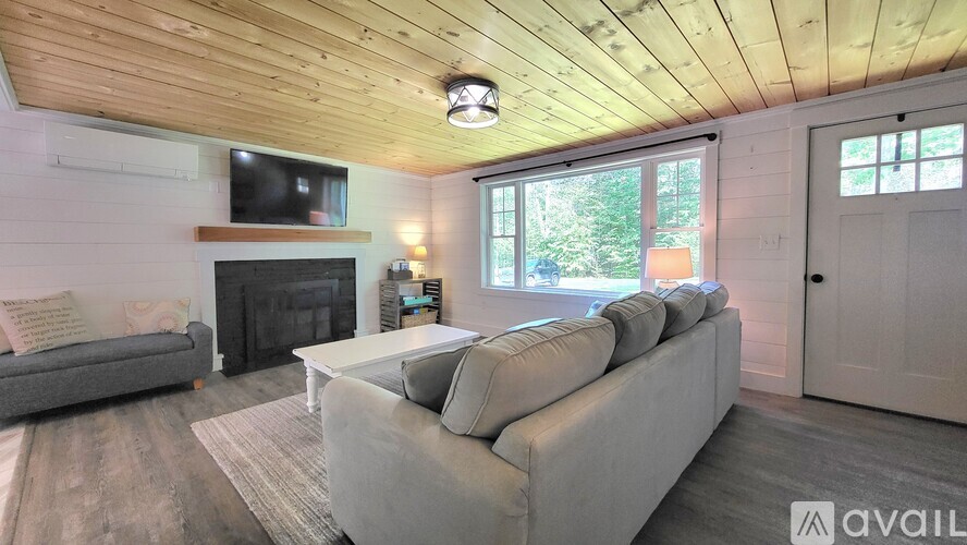 A living room with a grey couch, a fireplace, and a television mounted on the wall.