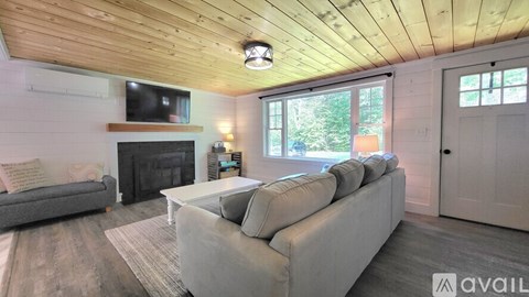 A living room with a grey couch, a fireplace, and a television mounted on the wall.