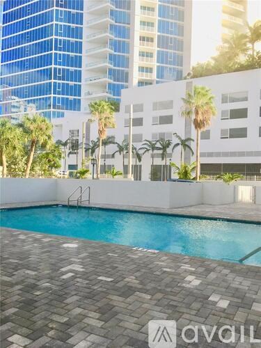 A pool surrounded by palm trees and buildings.