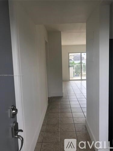 A hallway with a tiled floor and a door on the left.