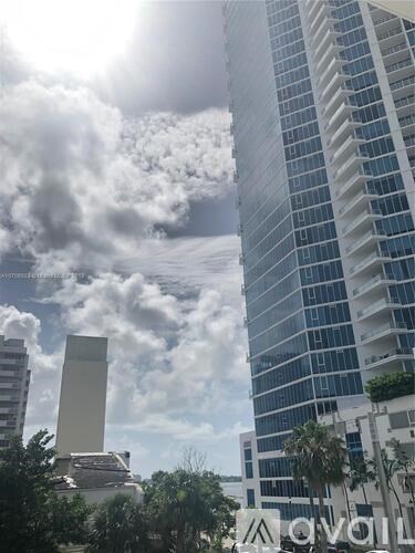 A tall building with a glass facade stands under a cloudy sky.