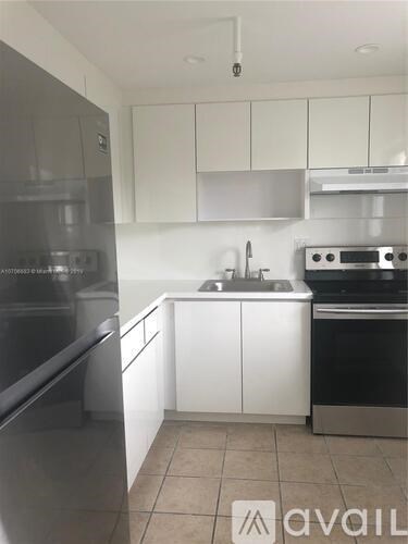 A kitchen with white cabinets and a black fridge.