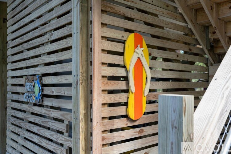 A pair of orange flip flops hanging on a wooden wall.