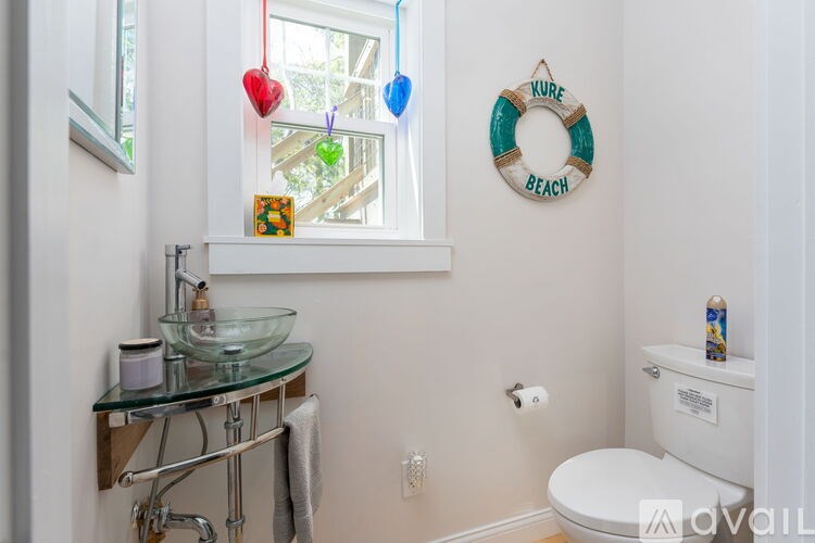 A bathroom with a glass sink and a toilet.