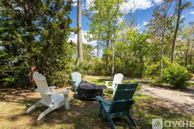 Two chairs are placed on the grass in a sunny backyard.