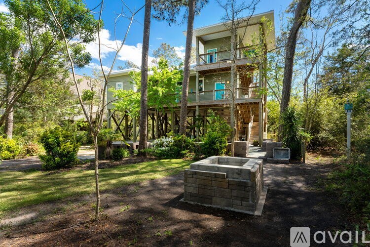A modern two-story house with a balcony is surrounded by greenery.