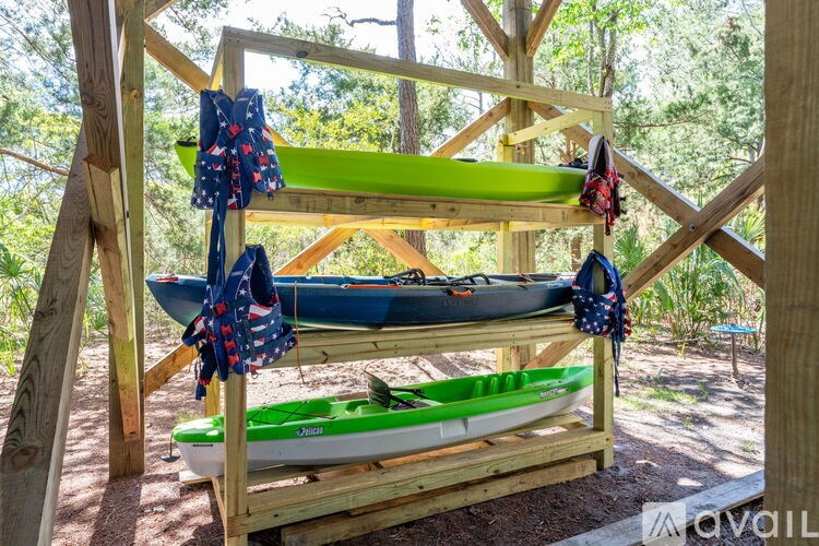A green kayak is stored on a wooden rack with a blue kayak in the background.