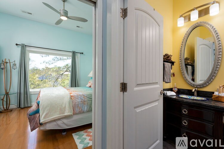 A bedroom with a bed, dresser, mirror, and a window with curtains.