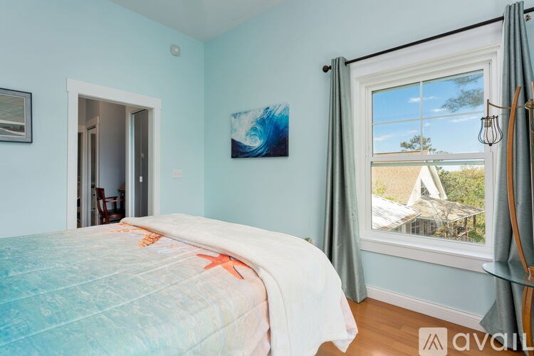 A bedroom with a bed, a window, and a painting on the wall.