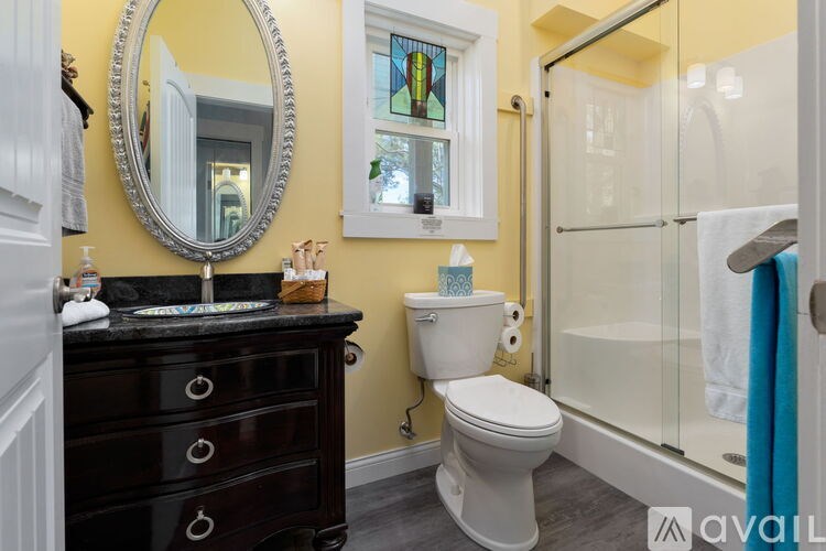 A bathroom with a toilet, sink, mirror, and shower.