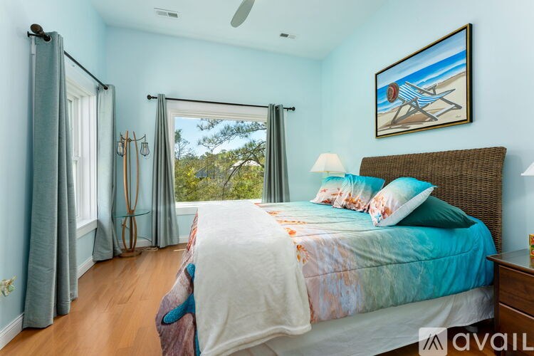 A bedroom with a bed, a ceiling fan, and a painting on the wall.