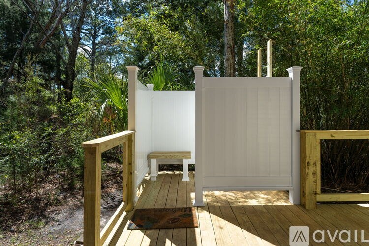 A wooden deck with a white fence and a bench in the middle of it.