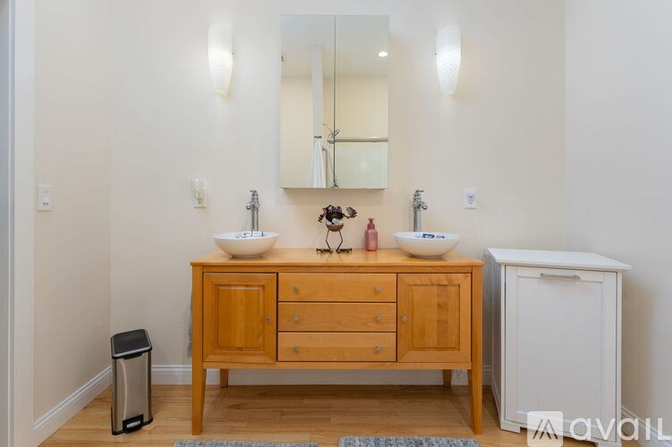A bathroom with a wooden vanity and a mirror above it.