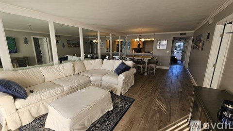 A spacious living room with a white sofa and a glass table.