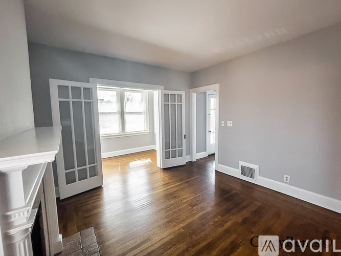 A spacious room with wood flooring and a fireplace on the left side.