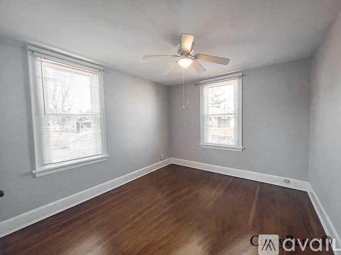 A room with wooden floors and two windows.