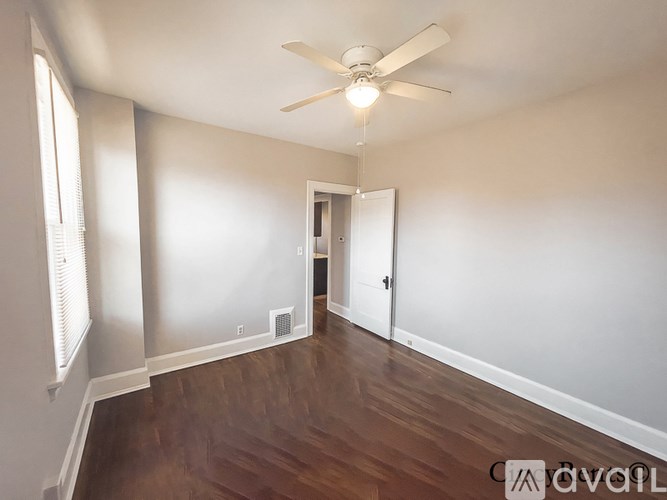 A room with a ceiling fan and wooden floors.
