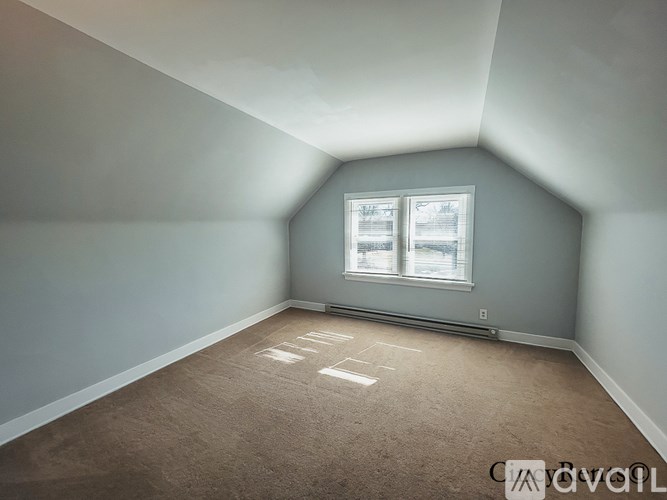 A room with a window and a carpeted floor.