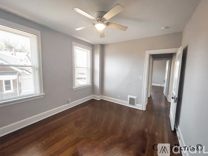A room with a ceiling fan and wooden floors.