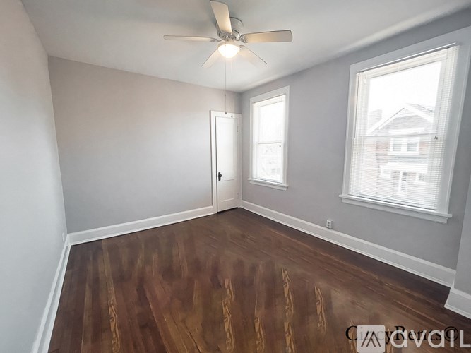 A room with a ceiling fan and wood flooring.
