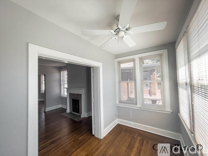 A room with a ceiling fan and a fireplace.