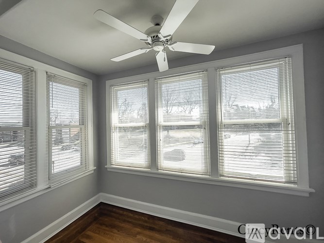 A room with a ceiling fan and three windows covered with blinds.