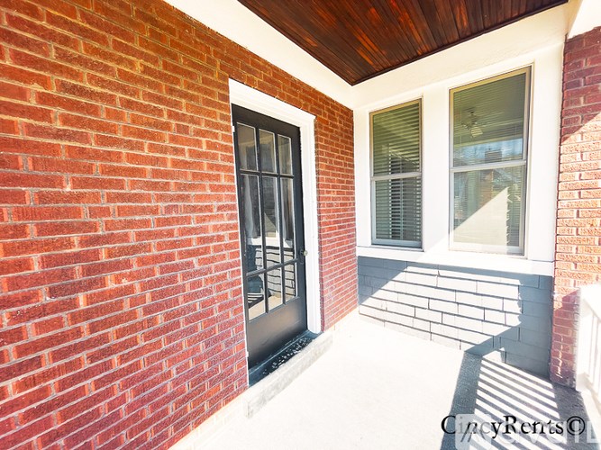 A red brick wall with a black door and a window.